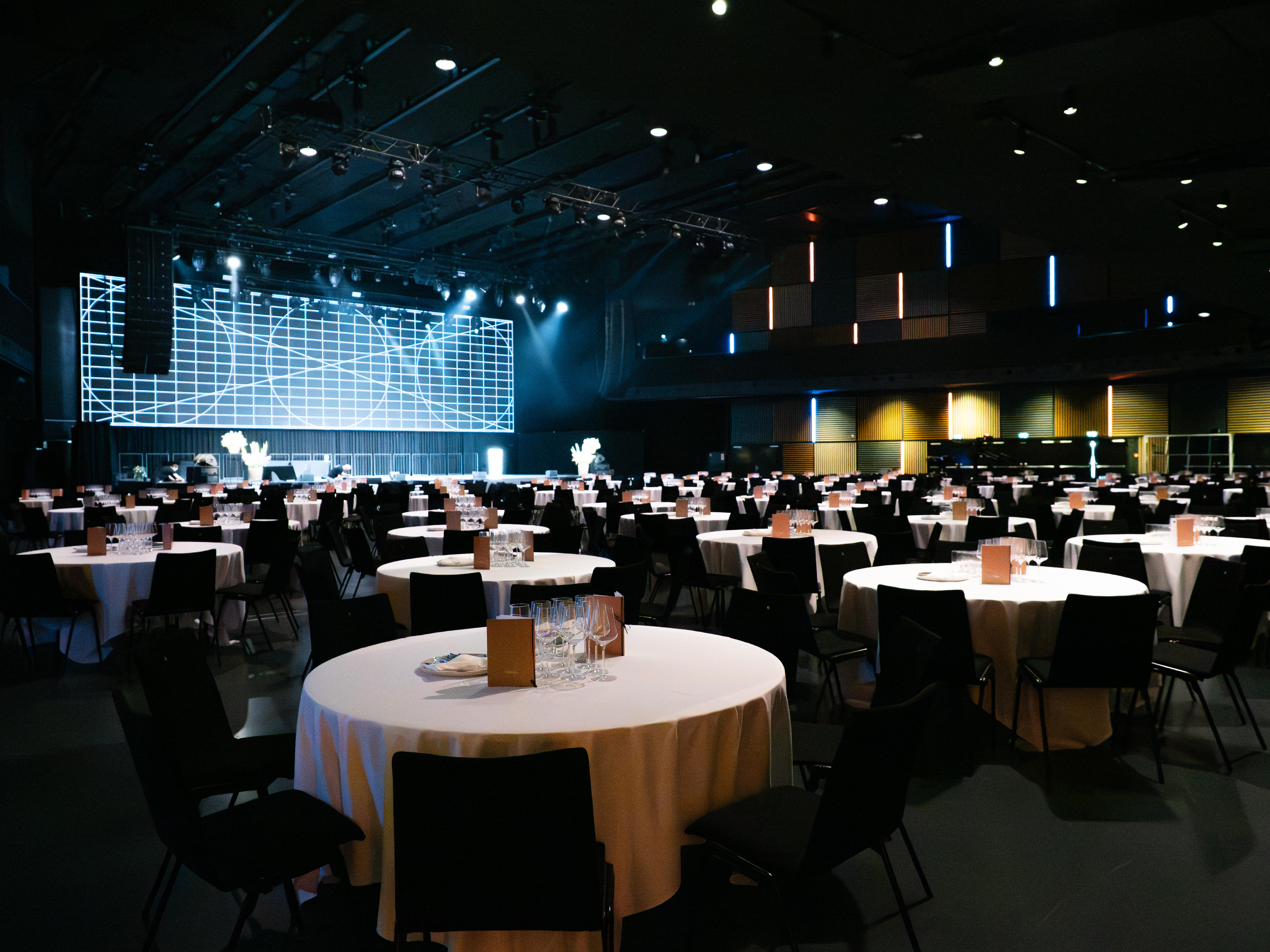 Gala-Setup in der HALL mit runden Tischen, Bühne und grosser LED-Wand.