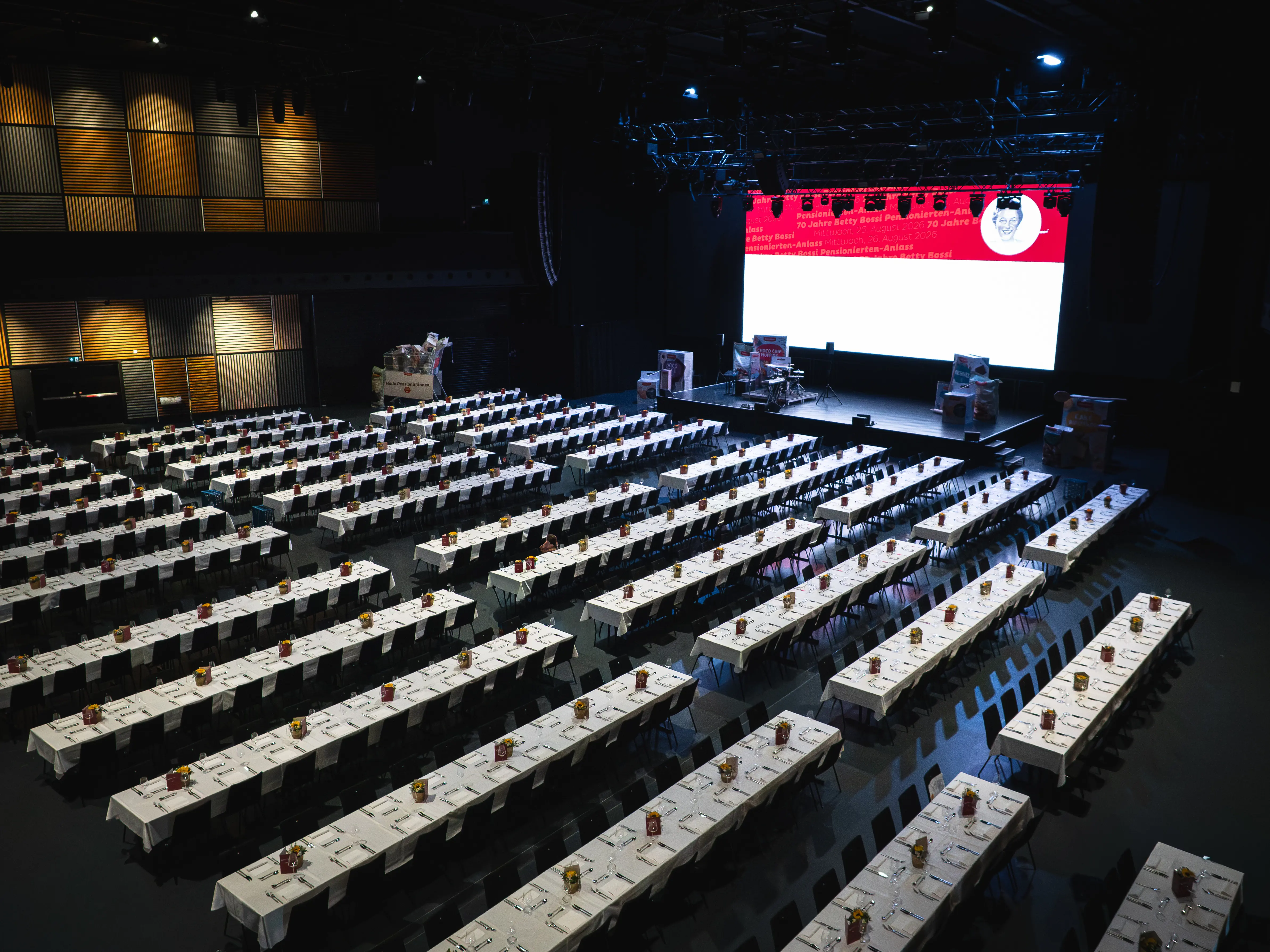 DIE HALL mit langen gedeckten Tischreihen und Bühne für den Coop Pensionierten-Anlass