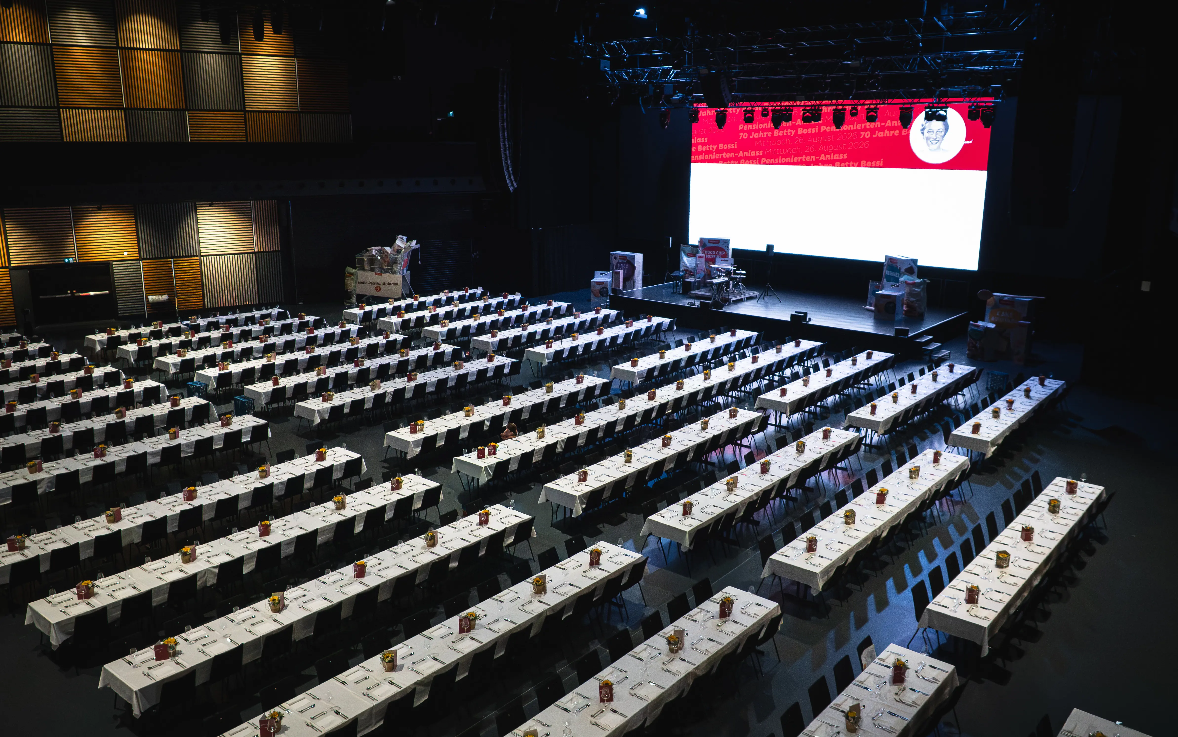 DIE HALL mit langen gedeckten Tischreihen und Bühne für den Coop Pensionierten-Anlass