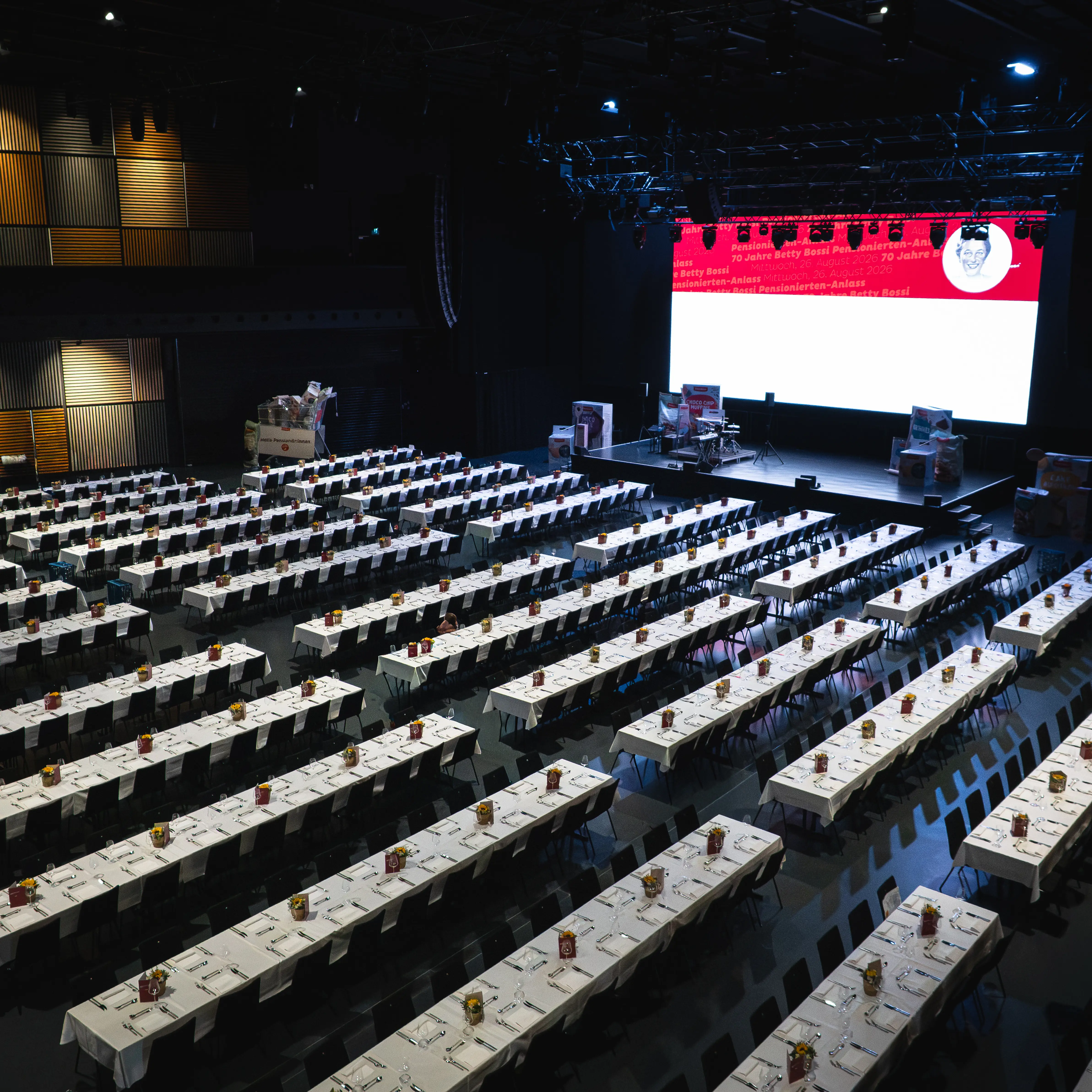 DIE HALL mit langen gedeckten Tischreihen und Bühne für den Coop Pensionierten-Anlass