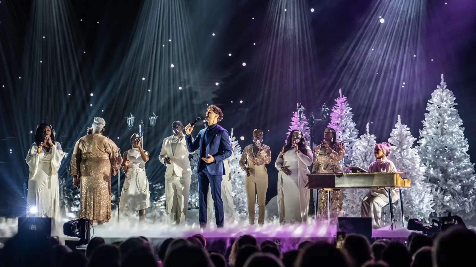 Ein Sänger inklusive Chor auf einer Bühne in weihnachtlichem Setting.
